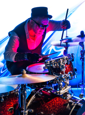 Drummer playing on drum set on stage in the color lightの写真素材