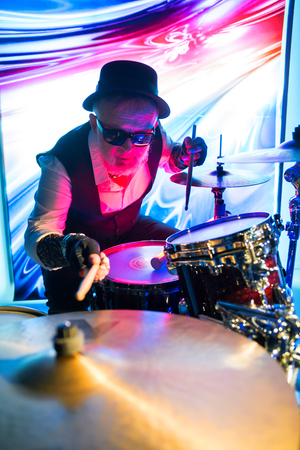 Drummer playing on drum set on stage in the color lightの写真素材
