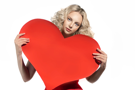 Beautiful blonde woman holding a heart paper model. Valentine day conceptの写真素材