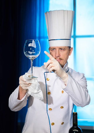 Chef in white uniform looks at a clean wine glassの写真素材