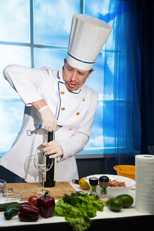 Chef in white uniform opens a bottle of wineの写真素材