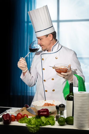 Chef in white uniform is tasting red wine from a glassの写真素材