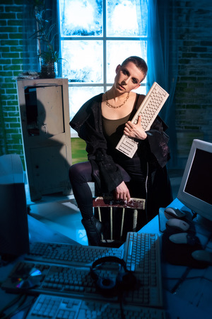 Female hacker with computer equipment and keyboard in handの写真素材