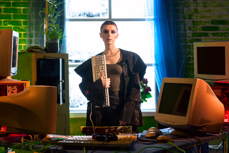 Female hacker with computer equipment and keyboard in handの写真素材
