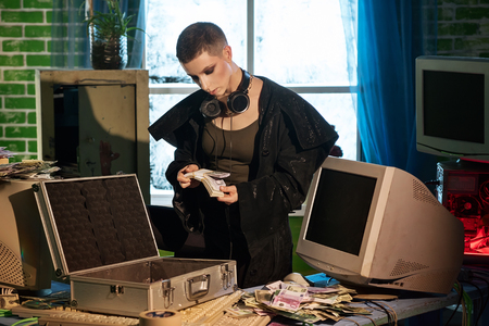 Female hacker with a currency and a computer equipmentの写真素材