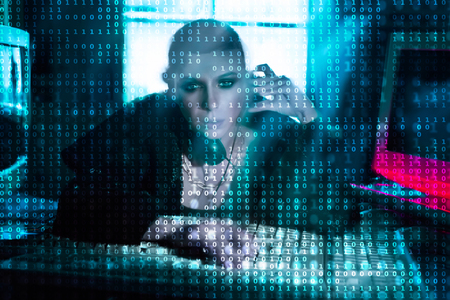Female hacker at the computer over code background