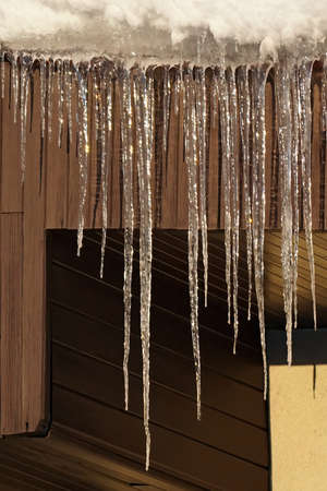 Icicles hanging from the roof on the blue sky background
