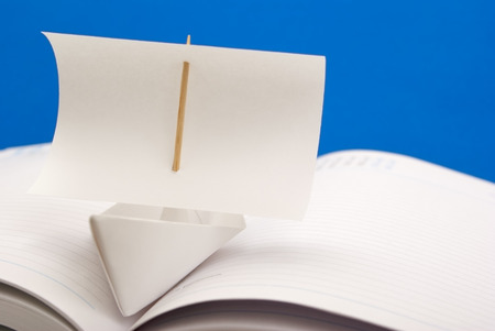 White paper ship with a sail on the notebookの写真素材