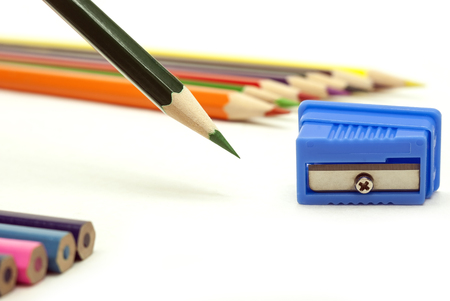 Green sharp pencil with a blue sharpener and colored pencils on white backgroundの写真素材