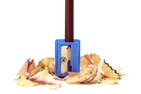 brown pencil in a blue sharpener with shaving on a white backgroundの写真素材