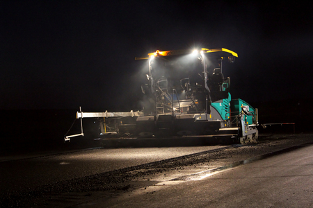 TULCEA, ROMANIA - DECEMBER 02: Tracked paver laying fresh asphalt pavement on a runway by night as part of the Danube Delta international airport on December 02, 2015 in Tulcea, Romania.のeditorial素材