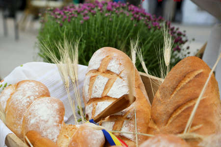 Fresh hearth bread in a wooden bowl in front of a bakery shopの写真素材