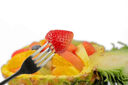 A fork with strawberry over a blurry background generated by an exotic fruits salad.の写真素材