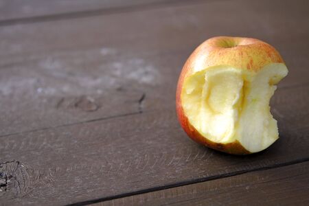 Still life with a bitten apple on a wooden table in a forest.の写真素材
