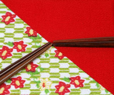 Two pairs of chopsticks on a specific piece of red Japanese fabric.の写真素材