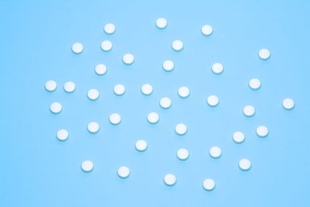 A medical background with white pills over a blue background- upper viewの写真素材