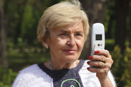 Senior woman using a mobile phone-selective focus on the phone,the woman face is out of focus.の写真素材