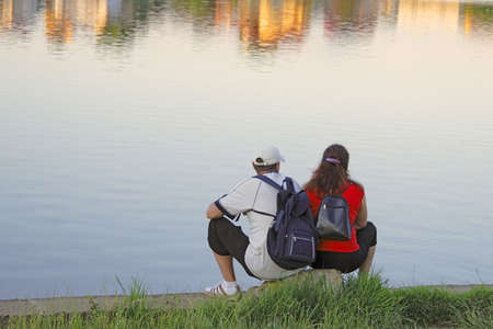 A couple admiring dusk city reflections in a lake.の写真素材