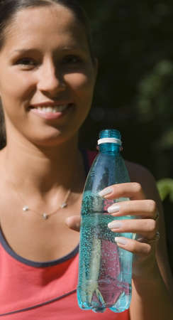 Image of a young woman with mineral water bottle after a workout sesion.Selective focus on the...