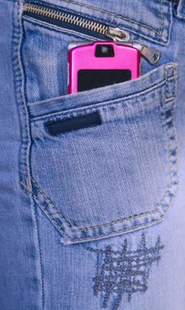 Close-up image of a pink mobile phone in a blue-jeans pocket.の写真素材