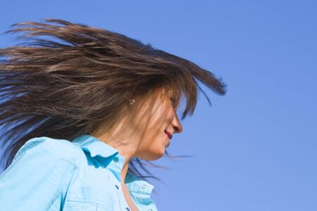 Young woman blowing her hair over the blue sky.の写真素材