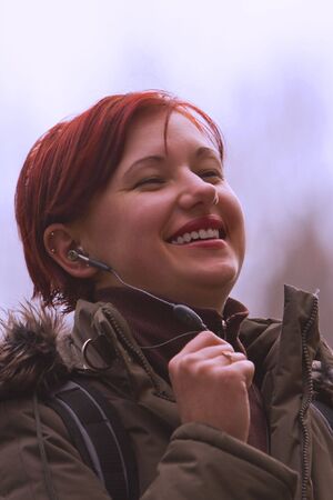 Redhead girl enjoying the music outdoor in the winterの写真素材