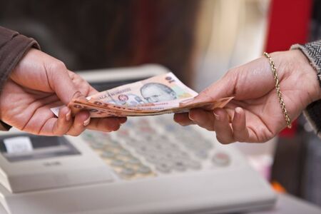 Detail of a woman's hand while she is paying in shop (Romanian money).