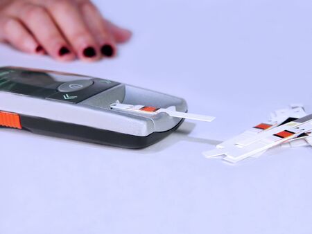 Glucometer-device for checking the blood glucose from the finger-focus on the device the hand is blurry.          の写真素材