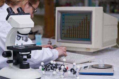 A female researcher analyzing some data at her lab desk.The image on the computer screen is...