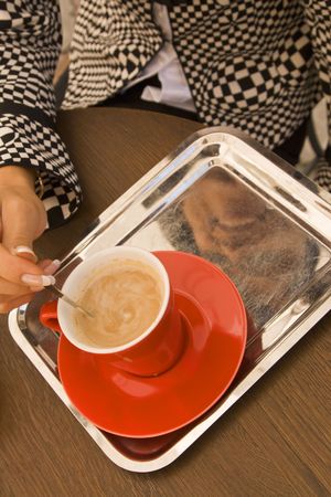Detail view of a woman's hand mixing the sugar in a coffee cup. の写真素材