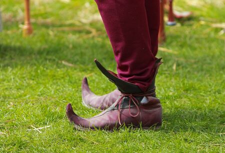 Close-up of specific medieval shoes (long toed shoes) on grass during a medieval festival. They have leather soles and multilayered leather heel made of specially hardened leather.They were popular in 12th-13th centuries in Europe.の写真素材