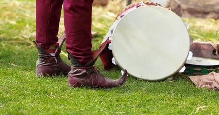 Close-up of specific medieval shoes (long toed shoes) on grass near a traditional drum during a medieval festival. The shoes have leather soles and multilayered leather heel made of specially hardened leather.They were popular in 12th-13th centuries in Euの写真素材