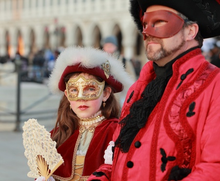 Venice,Italy,February 25th,2011: A girl wearing a traditional Venetian mask walking together with her father in San Marco Sqaure during the Carnival of Venice.The Carnival of Venice (のeditorial素材