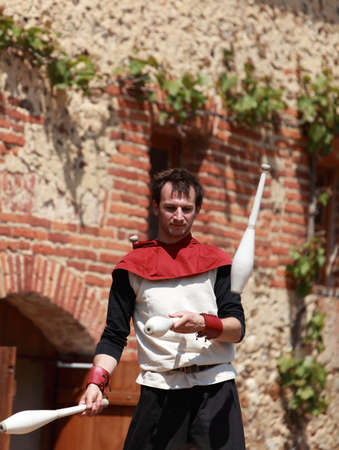 Arville,France,May 23rd 2010: Environmental portrait of a skittle juggler on stilts performing in the yard of the Commanderie of templars from Arville, during a Medieval Market show. Here is one of the best preserved Commanderie in France.のeditorial素材