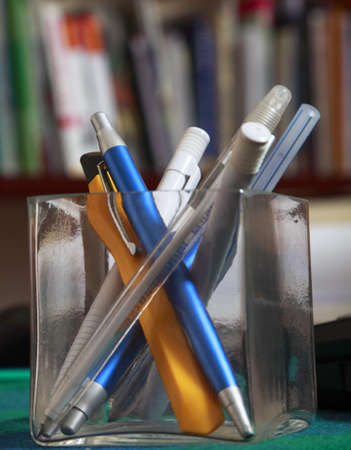 Image of different writing tools in a glass support on an office table.の写真素材