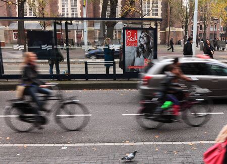 Amsterdam,The Netherlands- October 30th, 2011:Blurred image of car and people riding bicycles in a street in Amsterdam. Amsterdam is one of the most bicycle-friendly large cities in the world and is a centre of bicycle culture with good facilities for cycのeditorial素材