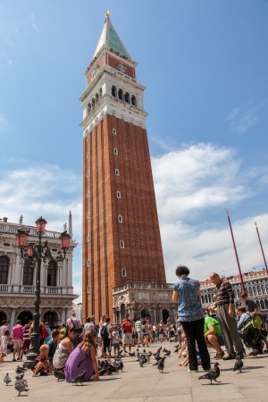 Venice,Italy,July 28, 2011: Tourists enjoying the pigeons in front of the Campanille in San Marco Square in Venice.のeditorial素材