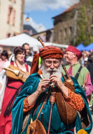 Montmedy, France, April 29th, 2012: Image of aa old street piper performing in a street in front of a traditional band during a reenactment medieval festival in Montmedy, France.のeditorial素材