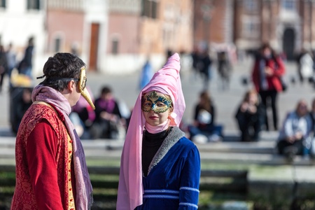 Venice, Italy- February 26th, 2011: A young couple with traditional Venetian mask discussing on the edge of a canal in Venice during the Carnival days.のeditorial素材