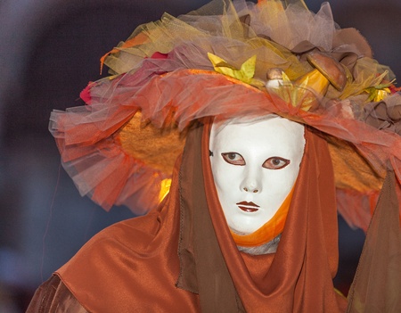 Venice, Italy- February 26th, 2011:Environemntal portrait of a person wearing a specific orange costume and a mask during the Venice Carnival nights.のeditorial素材