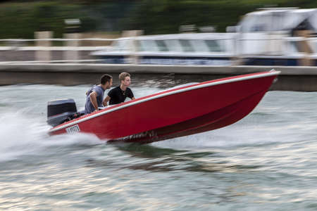Venice, Italy- July 30,2011: Two young men cruising the waters near Venice in a red high speed boat.のeditorial素材