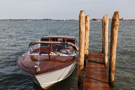 Motorboat docked near the wooden poles in Venice.の写真素材