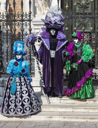 Venice, Italy- February 18th, 2012: A group of three disguised people posing in front of a traditional building during the Venice Carnival days.のeditorial素材