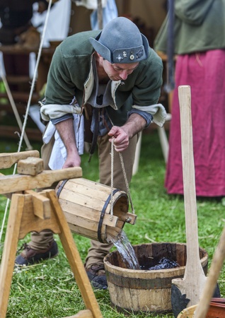 Nogent le Rotrou,France-May 19,2012:Medieval man pouring water for the food preparation outside in fornt of the tent during a reenactment festival around the St. Jean Castle in Nogent le Rotrou.のeditorial素材