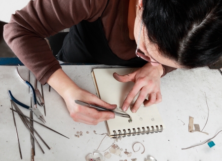 Bird eye view of a female jeweler working in her workshop.