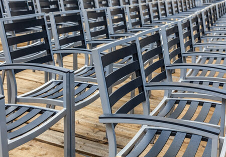 Row of wet chairs on a wooden floor located outdoors in a rainy day.の写真素材