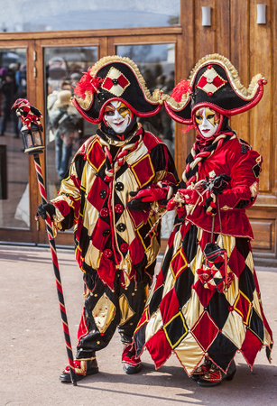 Annecy, France, February 24, 2013  Portrait of an unidentified couple disguised in red jesters costumes pose in front of a traditional store in Annecy during a Venetian Carnival, which celebrates the beauty of the real Veniceのeditorial素材