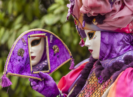 Annecy,France-March 15,2014 Environmental portrait of a person in a mask looking in a mirror during the Annecy Venetian Carnival  Yearly in Annecy ,France is held a Venetian Carnival to celebrate the beauty of the real Venice のeditorial素材