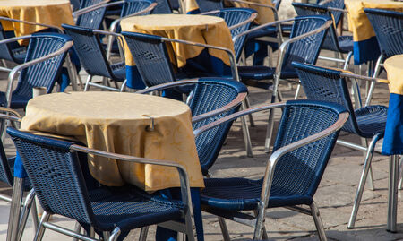 Image of a beautiful and bicolor Venetian street restaurant terrace with rattan chairs.の写真素材