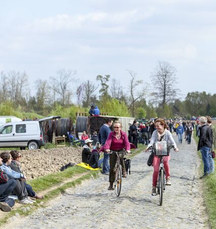 CAMPHIN EN PEVELE,FRANCE-APR 13: Two casual women cycling on the cobblestone sector Carrefour de Arbre in Camphin-en-Pevele on April 13 2014 during Paris-Roubaix cycling raceのeditorial素材